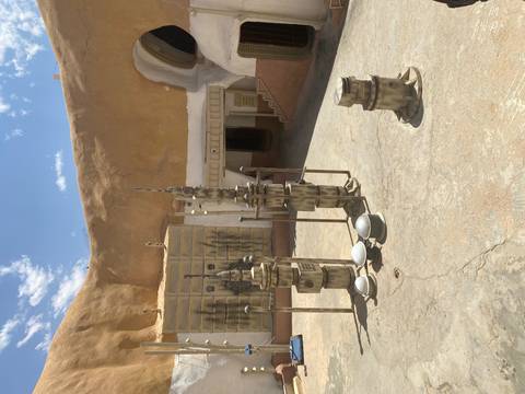 A courtyard with sci-fi structures against an earthen backdrop.