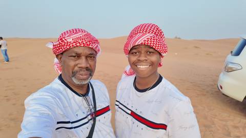 Two people wearing headscarves standing in the desert.