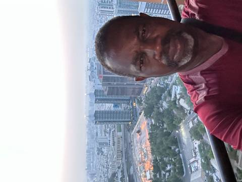 Person taking a selfie with a city view in the background.