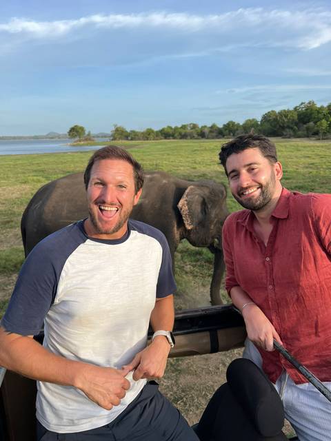       Two people smiling with an elephant in the background.
  