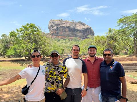       Group of people posing in front of Sigiriya rock.
  