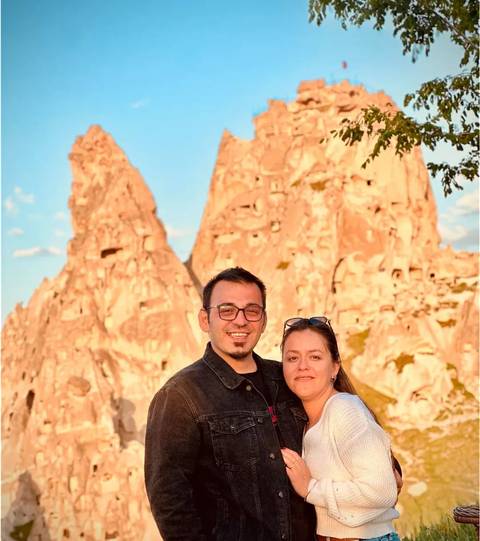       Couple in front of distinctive rock formations in sunset light.
  