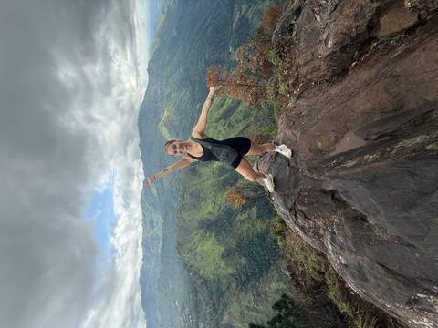 Woman posing on a rocky mountain with a scenic view.