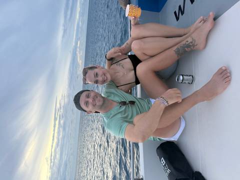       Couple sitting on a boat with ocean in the background.
  