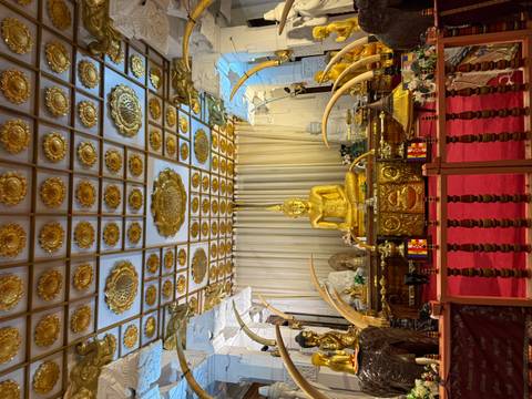 Interior view of a temple with a golden Buddha statue and elaborate decorations.