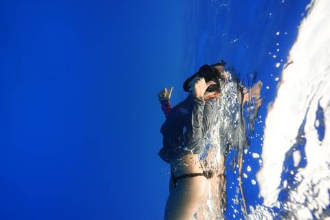 Person snorkeling underwater in clear blue waters.