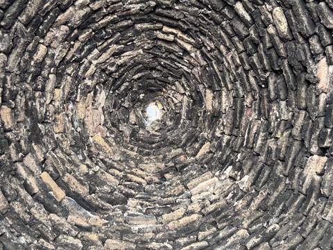       Close-up of a spiral brick structure, possibly a well.
  