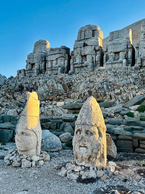 Statues of heads with mountainous background.