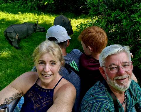 Group of people on a safari with rhinos in the background.