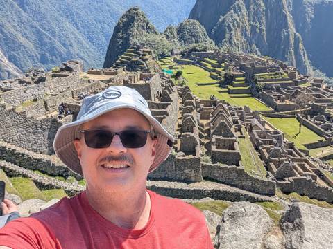 Man taking a selfie at Machu Picchu with ruins in the background.