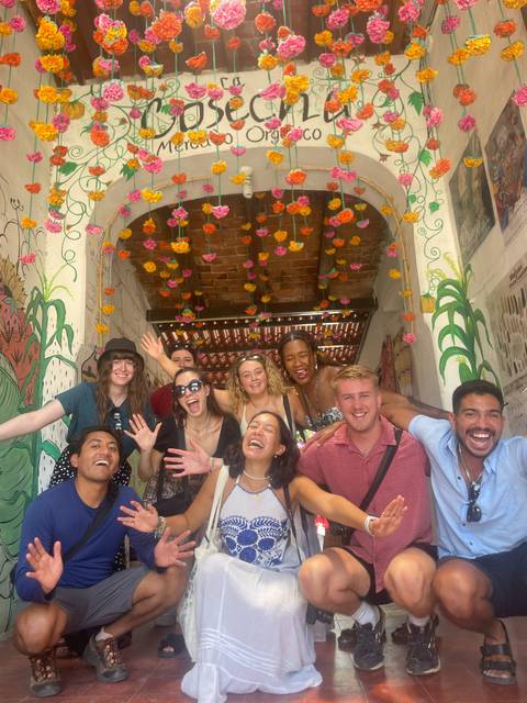       Group of people cheerfully posing under flower decorations.
  