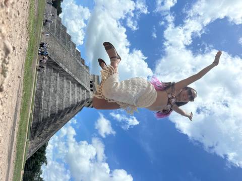       Woman jumping in front of an ancient pyramid.
  