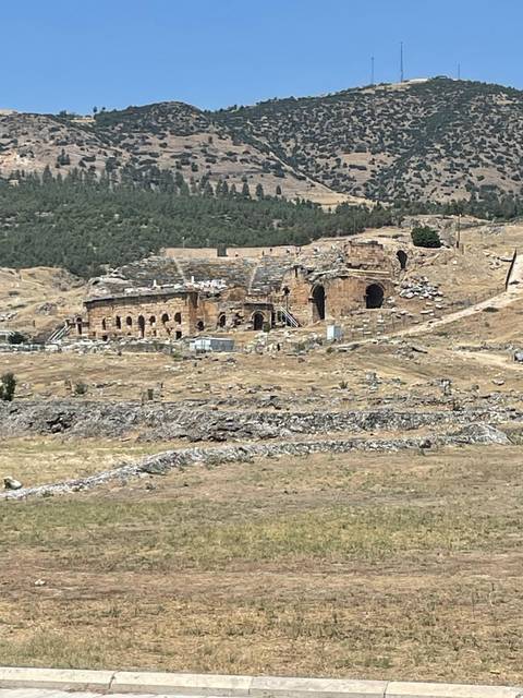 Ruins of an ancient amphitheater on a hillside.