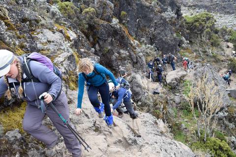      Hikers ascending a rocky mountain trail.
  