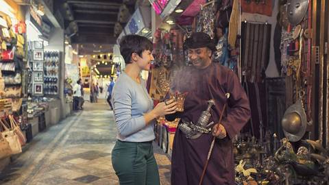       Woman interacting with a man inside a market filled with cultural items.
  