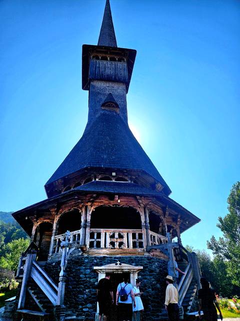 A tall wooden and brick building with a steep roof.