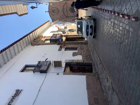       Street with shops and a parked car under clear blue sky.
  