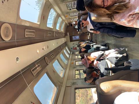       Interior of a train with passengers and large windows.
  