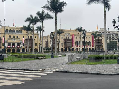       Plaza with colonial buildings and palm trees.
  
