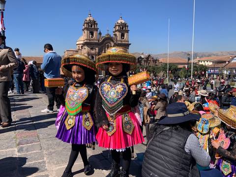       Children in traditional Peruvian costumes in a plaza.
  