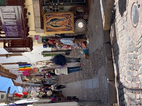       Cobbled street market with colorful textiles for sale.
  
