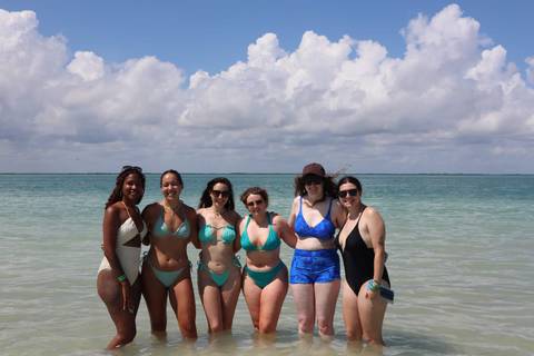       Group of people posing in swimwear by the sea.
  