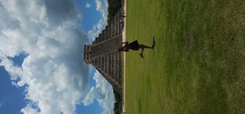       Person posing in front of the Pyramid of Chichen Itza.
  