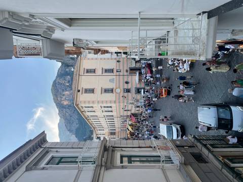       Bustling street with buildings and mountains in the background.
  