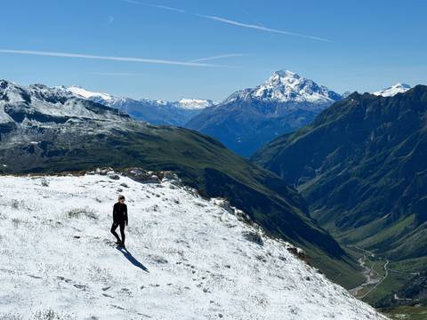 A person standing on a snowy mountain with vast landscapes.