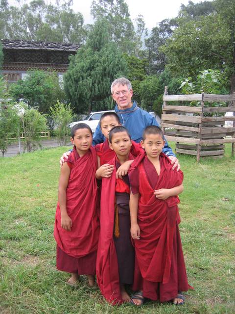 Group of boys wearing traditional red robes posing with an adult.