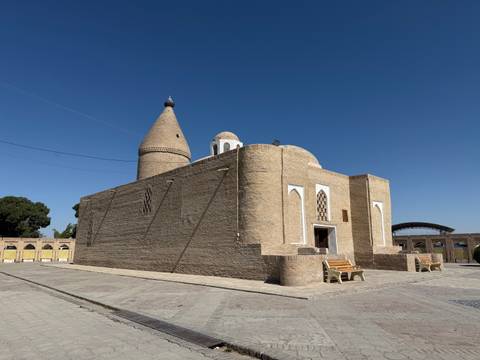 Ancient walled structure with conical towers under blue sky.