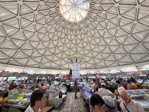 Busy market under a large dome with geometric patterns.