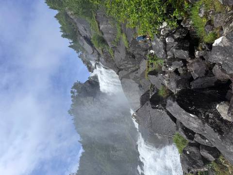       Waterfall with a mist against a mountain backdrop.
  