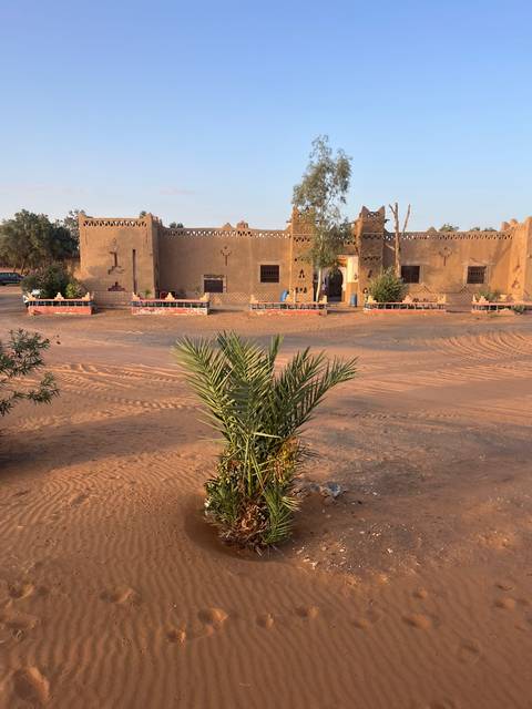 Low-lying building in desert setting with vegetation.