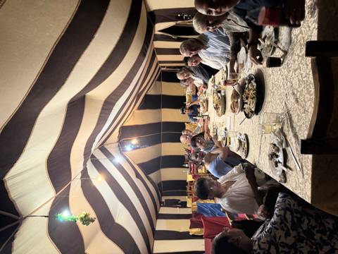 Dining table inside a tent with people eating.