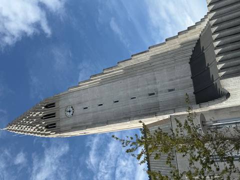 Distinctive concrete church with a clock tower against a blue sky.