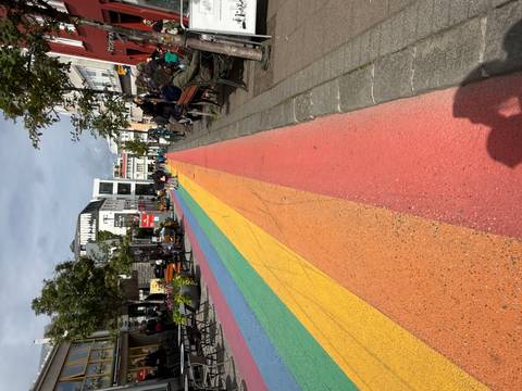 Rainbow-painted pedestrian street in an urban setting with people walking.