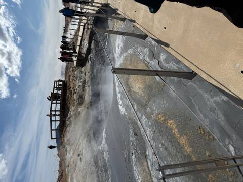 Steaming geothermal field with tourists observing.