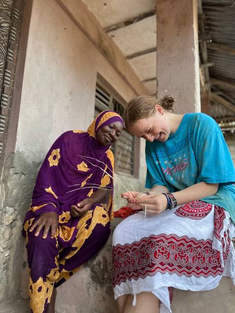       Woman and local artisan weaving together and smiling.
  