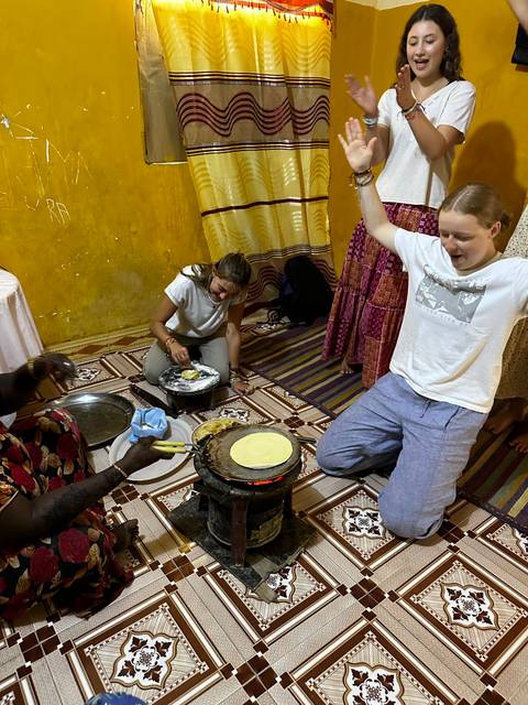       Group of people cooking and laughing in a lively kitchen.
  