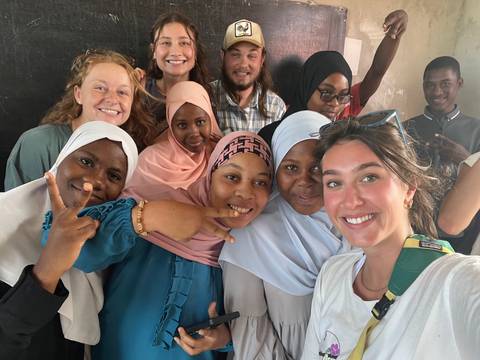       Smiling group of people, including locals, posing together for a selfie.
  