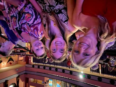       Three women smiling in a theater setting.
  
