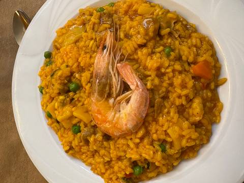       A dish of paella with a shrimp on top.
  