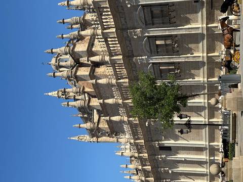 A grand historic building with spires set against a clear blue sky.