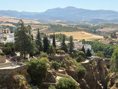       A scenic view of hills, fields, and a bridge, with distant mountains.
  