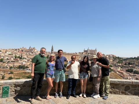       Seven people posing in front of an elevated view of a city with historical buildings.
  