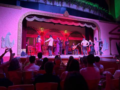 A live performance with dancers and musicians on a stage with vibrant lighting.