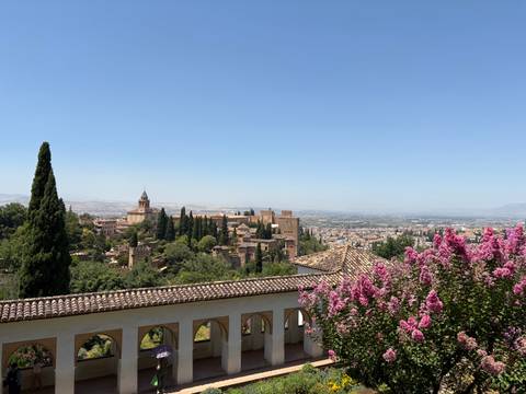 A view over a garden with historic buildings and a clear sky.