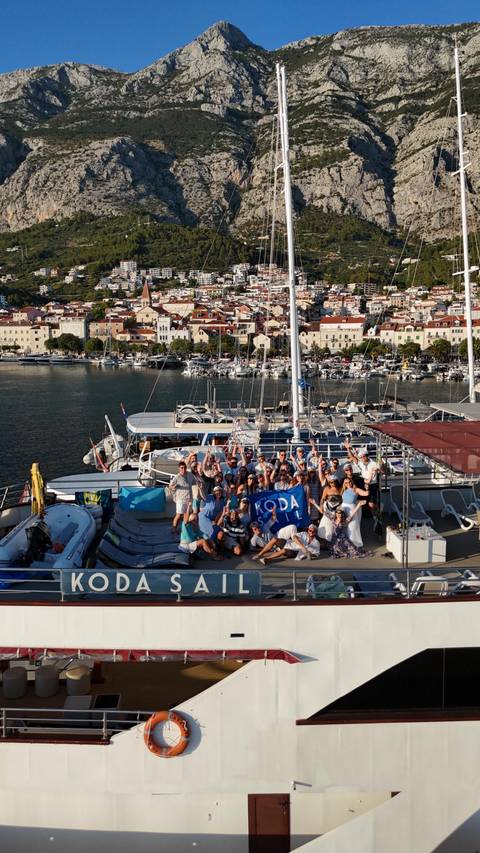       Large group of people posing on a boat with a city backdrop.
  