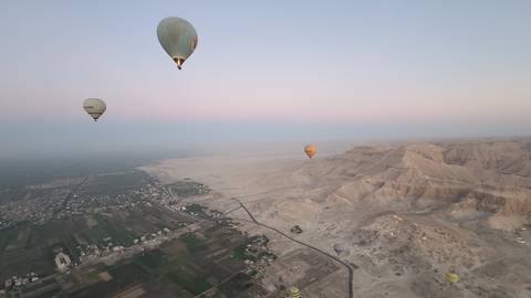 Hot air balloons floating over a desert landscape at dawn.
